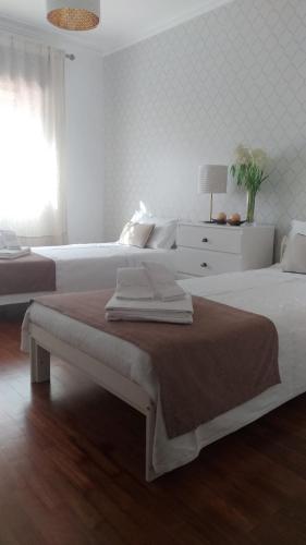 a white bedroom with two beds and a window at Casa O'lado in Golegã
