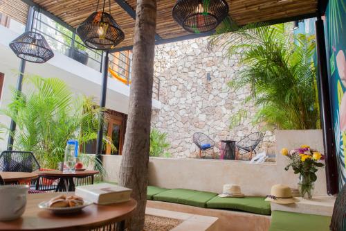 Un patio con mesas y sillas y un muro de piedra. en Latino Hotel Boutique, en Tulum