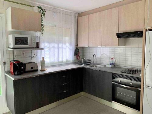 a kitchen with brown cabinets and a sink and a microwave at Lilo 30, Only Families, Puy du Fou in Olías del Rey