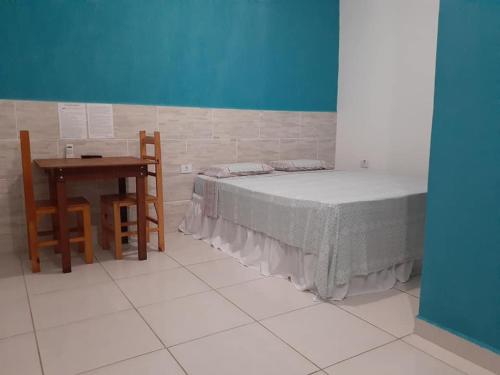 a room with a bed and a table and a table and chair at Pousada Ancoradouro in Cananéia