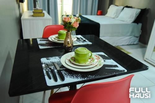 a black table with two cups and plates and a vase of flowers at Estudio no West Flat Mossoró - Alto Padrão in Mossoró