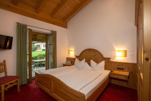 Schlafzimmer mit einem großen Bett mit einem Kopfteil aus Holz in der Unterkunft Landhaus Stephanie in Krün