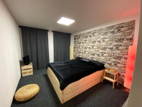 1 dormitorio con cama y pared de ladrillo en WELLNESS APARTMÁN KAROLÍNA, en Milovice