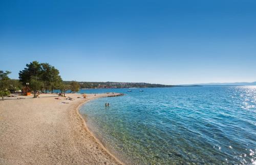 a beach with people swimming in the water at Aminess Younique Gaia Green Villas in Njivice