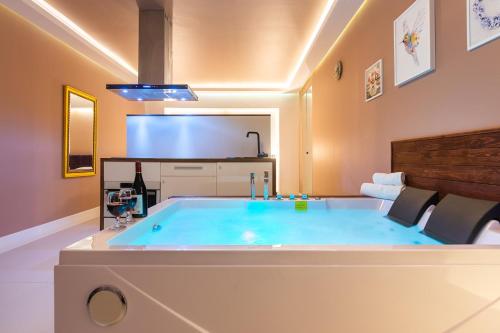 Cette chambre dispose d'une télévision et d'une grande baignoire bleue. dans l'établissement Lilly De Luxe Apartment with jacuzzi, à Michałowice