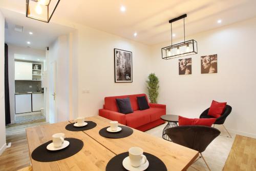 un salon avec une table et un canapé rouge dans l'établissement Rent a Room - Tracy apartment, à Paris