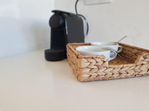 a basket with two cups and a coffee maker at Sol Da Caparica in Costa da Caparica