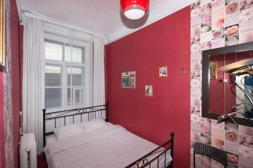a bedroom with a red wall with a bed and a window at Loft Hostel Minsk in Minsk