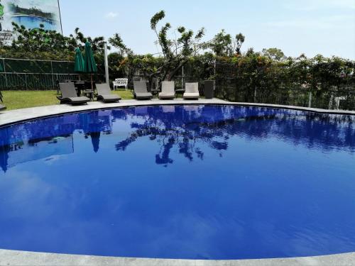 uma grande piscina azul com espreguiçadeiras num quintal em Memora Chapala em Chapala