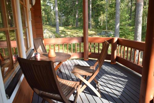 un porche con 2 sillas y una mesa. en Honeyhill Villa Karhu, en Isnäs