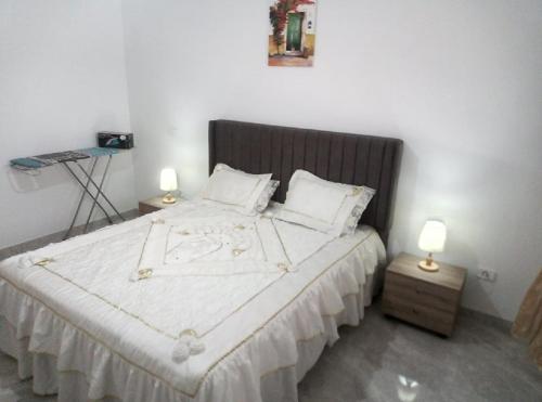 a bedroom with a large white bed with two lamps at Apparts zayatine in Tunis