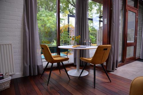 mesa y sillas en una habitación con ventana en BenB Het Posthuis en Nispen