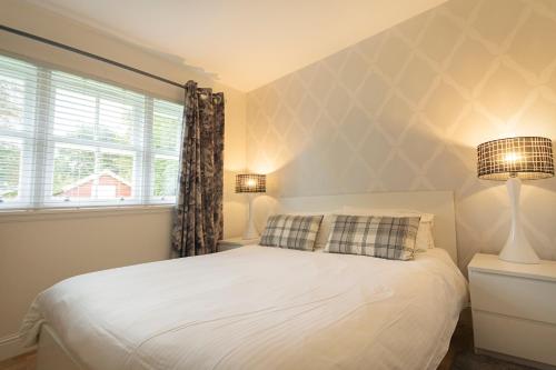 een slaapkamer met een bed, 2 lampen en een raam bij The Lodge House Callander in Callander