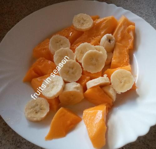a white plate of fruit with bananas and oranges at JoysVilla Family Holiday Home in Malindi