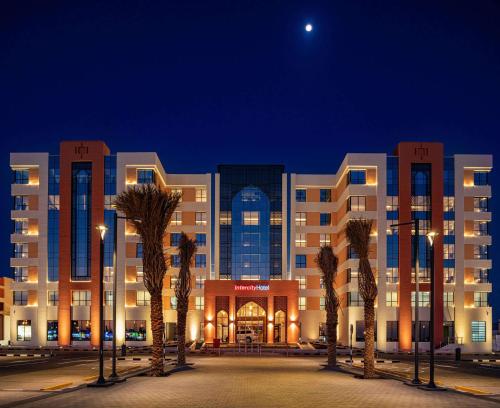 a building with palm trees in front of it at night at IntercityHotel Nizwa in Nizwa