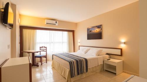 um quarto de hotel com uma cama e uma mesa em Aram Beach & Convention em João Pessoa