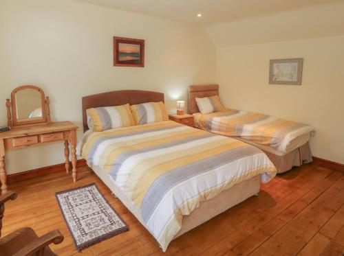 a bedroom with two beds and a wooden floor at Bron Gadair in Llanfairpwllgwyngyll