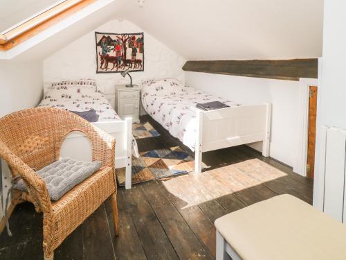 a attic bedroom with two beds and a chair at Penmaen House in Caernarfon