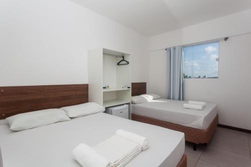 Habitación de hotel con 2 camas y ventana en Economy Suites, en Natal