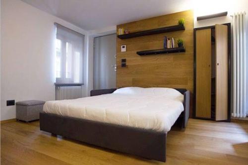 - une chambre avec un grand lit et un mur en bois dans l'établissement SPLENDIDO MONOLOCALE NEL CENTRO STORICO DEL BORGHETTO, à Ivrea