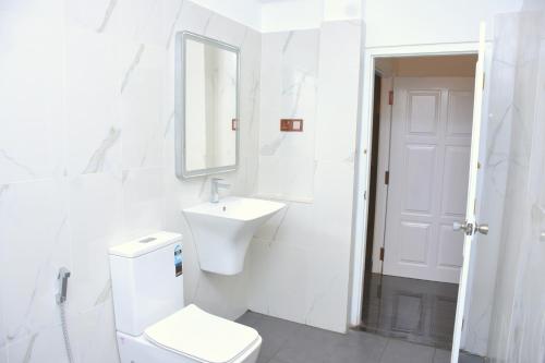 uma casa de banho branca com um WC e um lavatório em The Bamboo Tree Transit Hotel em Katunayaka