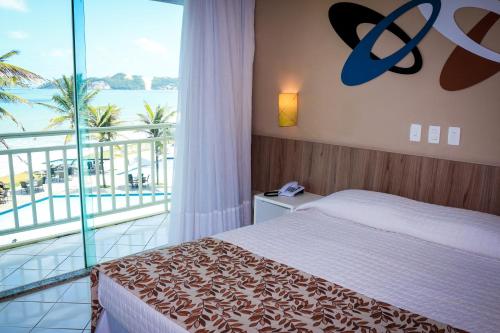 a bedroom with a bed and a view of the ocean at Aram Natal Mar Hotel in Natal