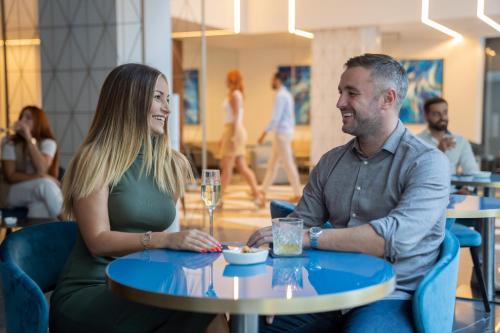 a man and woman sitting at a table in a cafe at Mercure St. Julian's Malta in St Julian's
