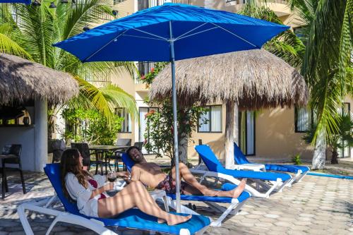 a group of people sitting in chairs under an umbrella at Hotel Posada del Mar in Isla Mujeres