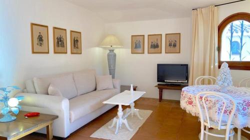 Sea & Beach Apartments Porto Cervo Costa Smeralda في بورتو كيرفو: غرفة معيشة مع أريكة وطاولة وتلفزيون