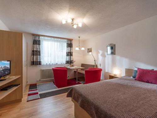 a bedroom with a bed and a table with red chairs at Haus Laimbauer in Kirchdorf in Tirol