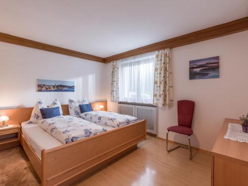 1 dormitorio con 1 cama y 1 silla roja en Haus Laimbauer, en Kirchdorf in Tirol