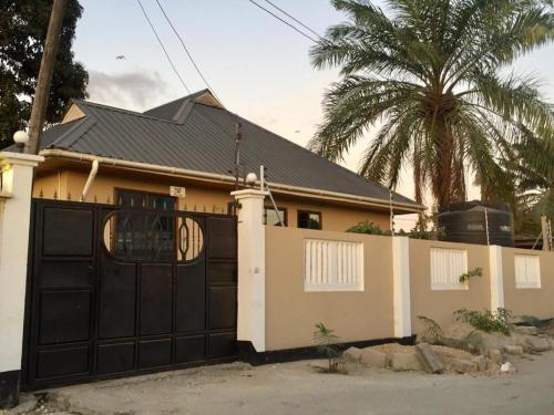 a house with a black garage door and a palm tree at Jfour comfort zone hostel in Dar es Salaam