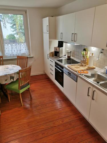 a kitchen with white cabinets and a table and a window at Ferienwohnung"Zur Birke" in Winsen Luhe