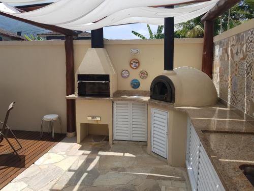 a outdoor kitchen with a pizza oven in a patio at Linda Casa em Juquehy in Juquei