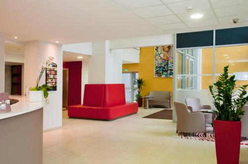 an office lobby with a red couch and chairs at Residhome Reims Centre in Reims