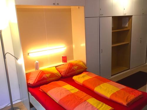 Zimmer mit einem Bett mit orangefarbenen und gelben Kissen in der Unterkunft Die mit dem roten Baum in Todtmoos