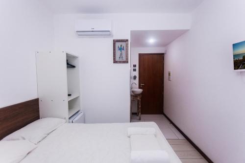 a bedroom with a white bed and a bathroom at Economy Apart in Natal