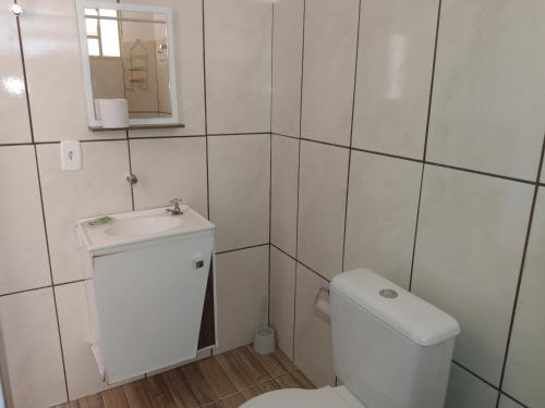 a white bathroom with a toilet and a sink at Recanto das Termas, Chalés in Termas do Ibirá