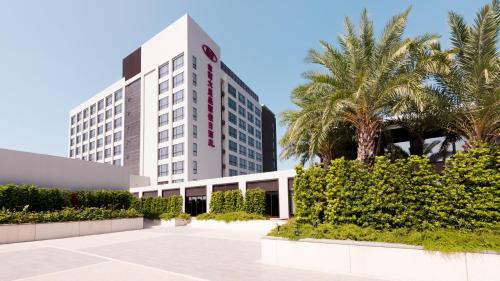 a tall white building with palm trees in front of it at Crowne Plaza Tainan by IHG in Tainan