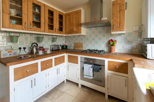 a kitchen with white cabinets and a stove top oven at Charming terraced cottage close to Alton Towers in Cheadle