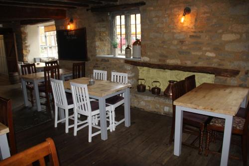 a dining room with a wooden table and chairs at The George Inn in Lower Brailes