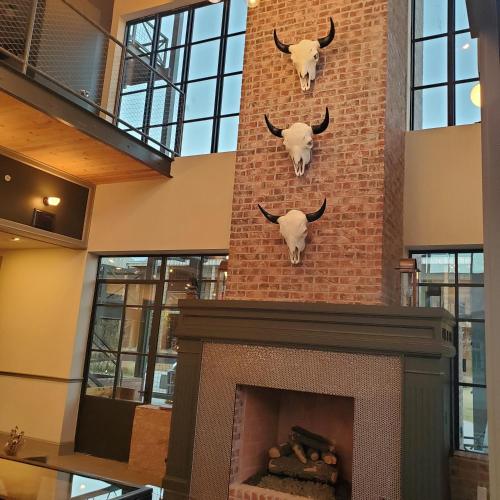 a fireplace with two bulls on a brick wall at Cotton Court Hotel, by Valencia Hotel Collection in Lubbock