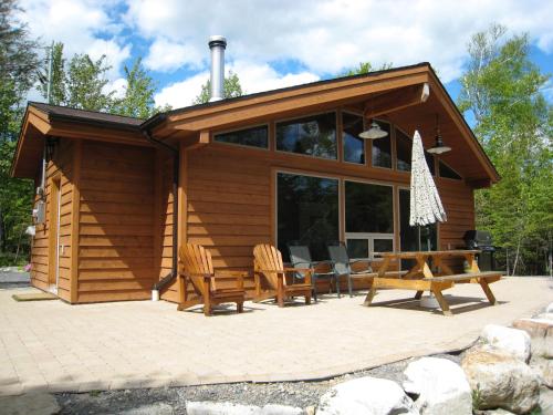 a log cabin with a picnic table and chairs at Les Chalets du Lac Grenier in Chertsey