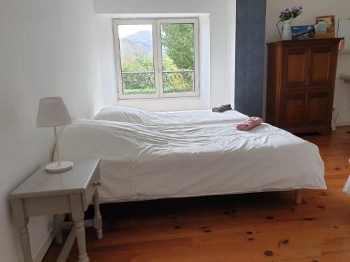 a bed in a room with a window at La bergerie, maison spacieuse avec grand jardin, vue sur les Pyrénées in Lourdes