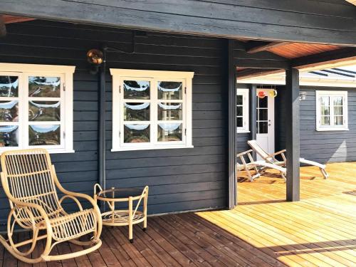 a black house with rocking chairs on a deck at 6 person holiday home in R m in Lakolk