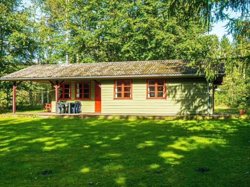 a small white house with red windows in a yard at 6 person holiday home in Toftlund-By Traum in Arrild