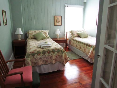 1 dormitorio con 2 camas, silla y ventana en Ardendales en Brooksville