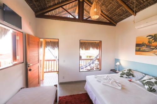 a bedroom with two beds and a door and windows at Pousada Aconchego da Pipa in Pipa
