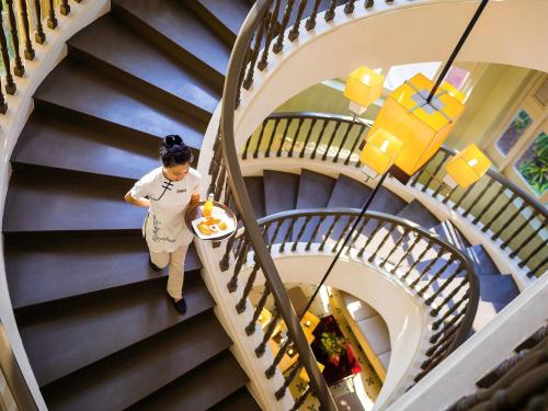 une femme marchant dans un escalier en colimaçon dans un bâtiment dans l'établissement La Veranda Resort Phu Quoc - MGallery, à Duong Dong