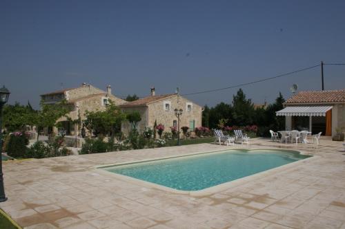 a pool in a yard with chairs and a house at Locations des Alpilles in Saint-Rémy-de-Provence